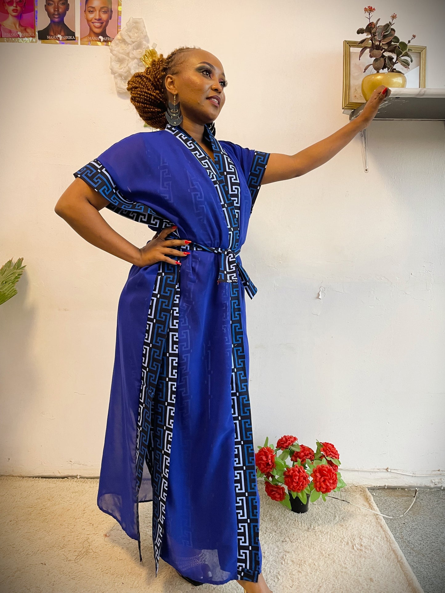 Woman in a blue dress with decorative patterns standing indoors.