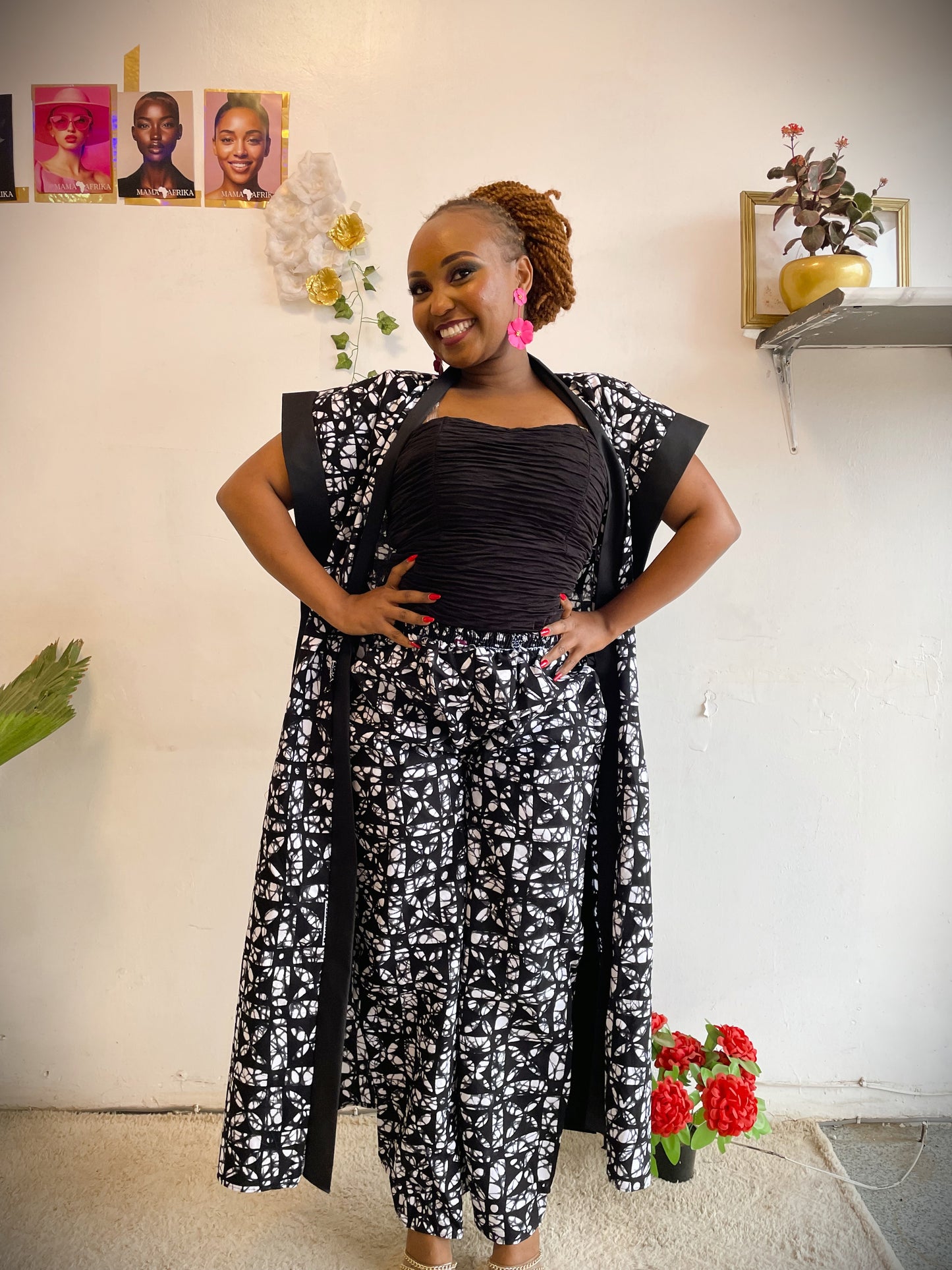 Woman wearing a black and white patterned outfit standing in a room with decor elements.