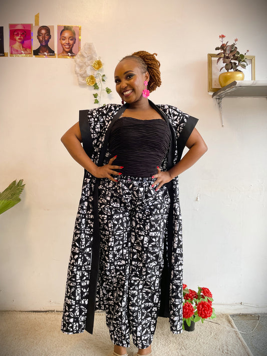Woman wearing a black and white patterned outfit standing in a room with decor elements.