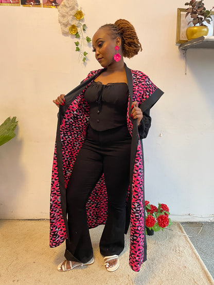 Person wearing a black and pink patterned coat with floral decorations on a light-colored floor.