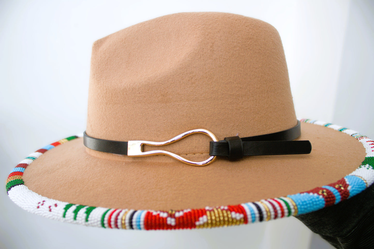 Beige hat with a colorful beaded band and black leather strap on a white background